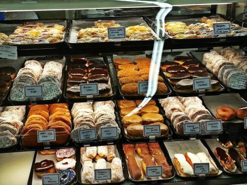 A display case filled with various pastries and donuts, showcasing a colorful assortment of baked goods.