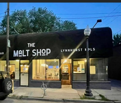 Exterior of The Malt Shop, a kitchen and bar in Lynnhurst, MPLS, featuring a black awning and a parked vehicle.