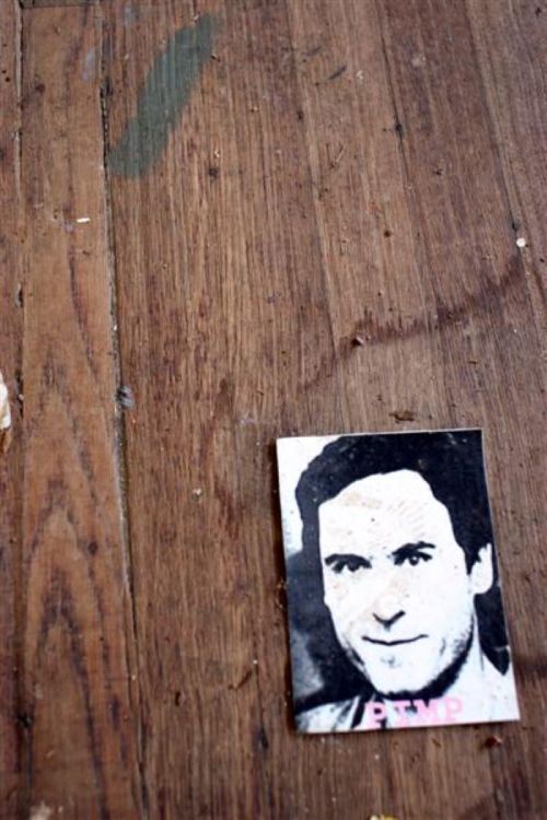 A worn wooden floor with a small, faded image of a man labeled "PIMP" beside it.