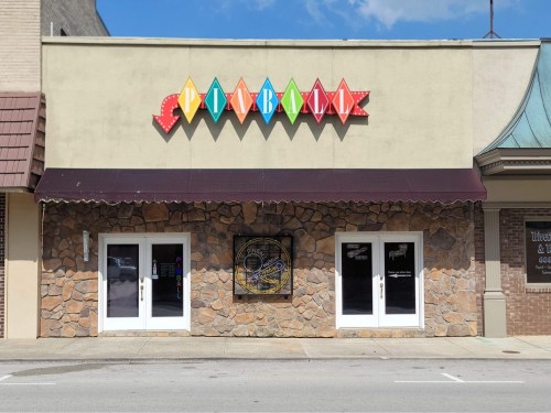 A colorful sign reading "Playhouse" above a stone-fronted building with double doors and a decorative mural.