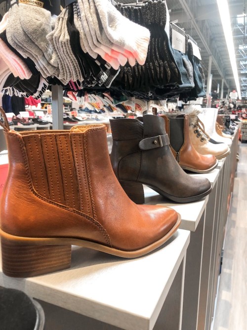 A display of various stylish ankle boots in brown and gray, with socks in the background.