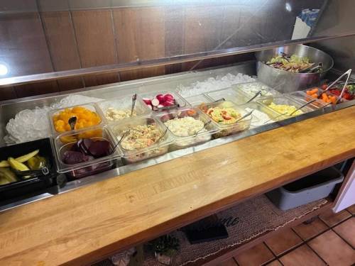 A buffet-style salad bar with various dishes, including salads, fruits, and vegetables, displayed on ice.