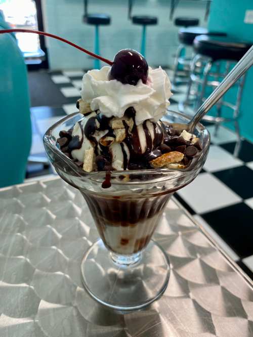 A delicious sundae in a glass, topped with whipped cream, chocolate syrup, nuts, and a cherry.