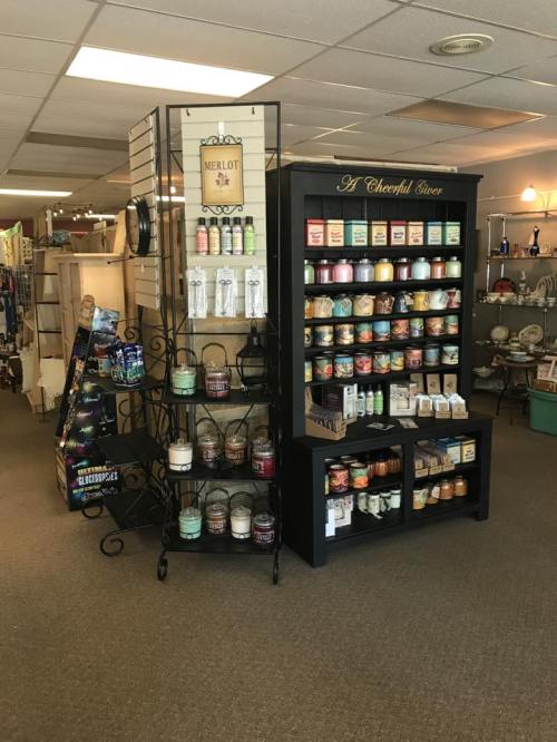 A cozy shop interior featuring shelves of colorful candles and home goods, with a warm, inviting atmosphere.