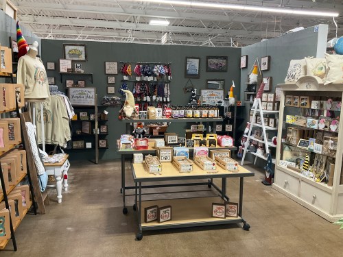 A cozy craft booth featuring handmade items, decor, and colorful displays on tables and walls.