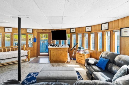 Cozy interior of a waterfront cabin with large windows, a sofa, and a small workspace.
