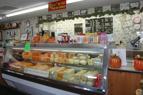 A cheese display case filled with various cheese types, surrounded by autumn decorations and a menu board in the background.