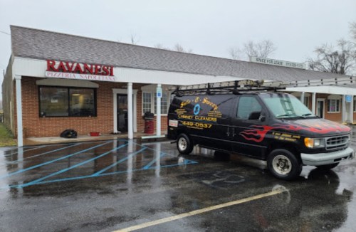 A black van with flames parked outside Ravaginesi Pizzeria Napolitano on a rainy day.