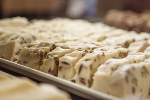 A close-up of a tray filled with neatly cut pieces of creamy white fudge with nuts.