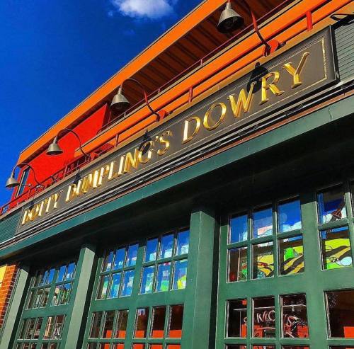 Sign for "Potty Dumplings Dowry" on a colorful building with blue sky and clouds in the background.