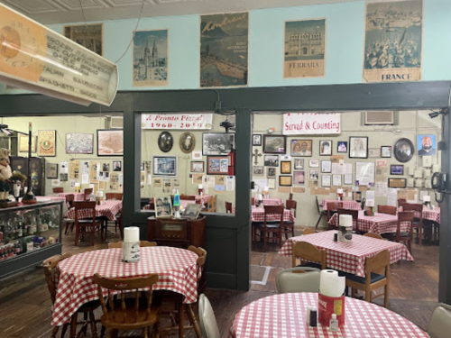 Cozy restaurant interior with checkered tablecloths, framed art, and vintage decor on the walls.
