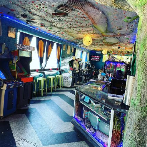 A colorful arcade with vintage games, neon lights, and a unique ceiling design, creating a vibrant atmosphere.
