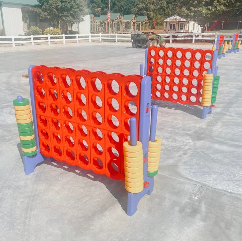 Two colorful connect-four style game boards set up outdoors on a playground surface.