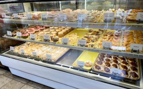 A display case filled with various baked goods, including cupcakes, pastries, and cookies, all neatly arranged.