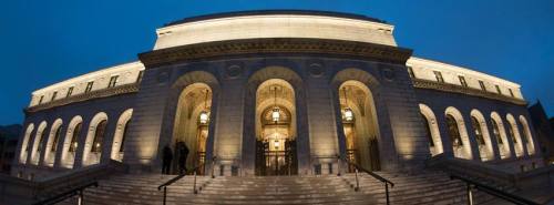 A grand building with illuminated arches and steps, captured at dusk.