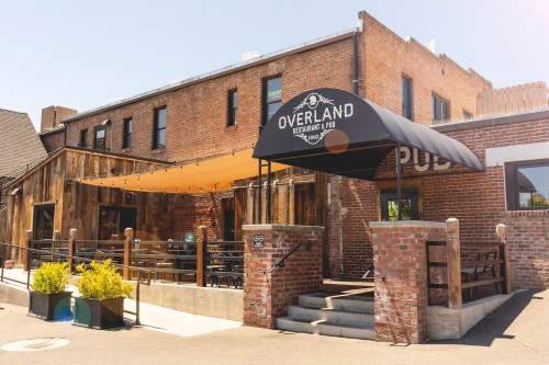 Exterior of Overland Restaurant & Pub, featuring a brick facade, awning, and outdoor seating area.