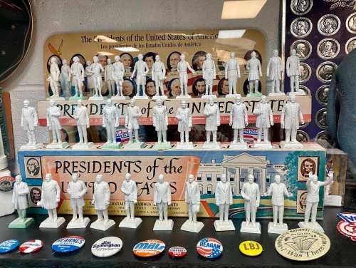 A display of miniature presidential figurines and campaign buttons, showcasing U.S. presidents and historical memorabilia.