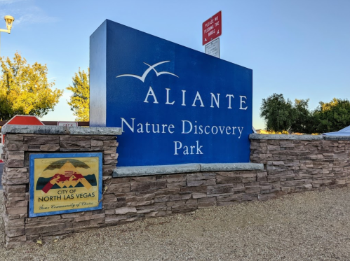 Sign for Aliante Nature Discovery Park in North Las Vegas, featuring a blue background and stone base.