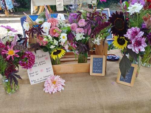 A table displaying colorful flower arrangements with price signs, set up at a market.