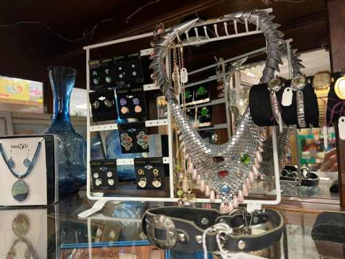 Display of various jewelry items, including a statement necklace, earrings, and bracelets, in a shop setting.