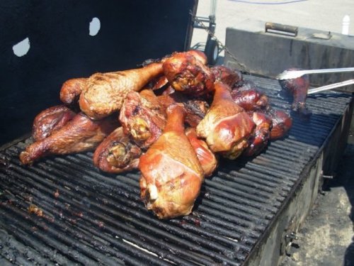 A grill filled with numerous smoked turkey legs, sizzling and ready to be served.
