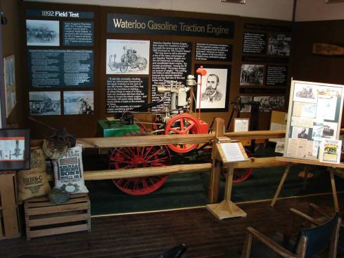 A museum display featuring the Waterloo Gasoline Traction Engine, with informational panels and historical artifacts.