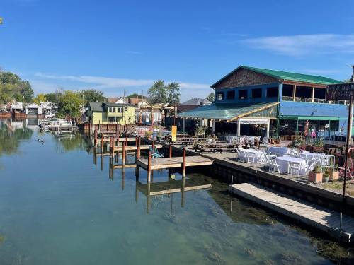 A serene waterfront scene featuring a dock, restaurant, and outdoor seating under a clear blue sky.