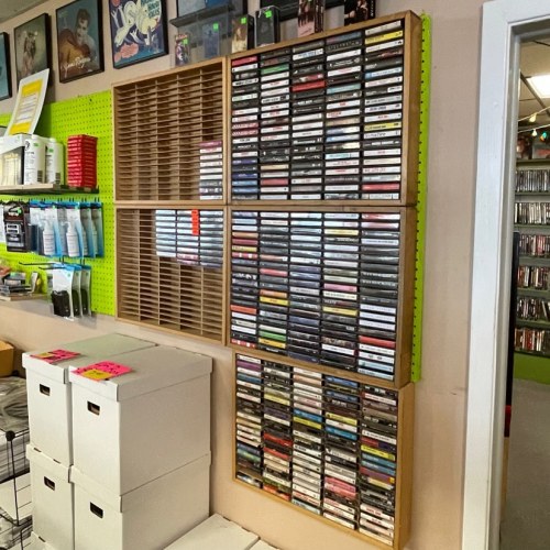 A wall display featuring shelves of cassette tapes, storage boxes, and colorful organizational materials in a retro setting.