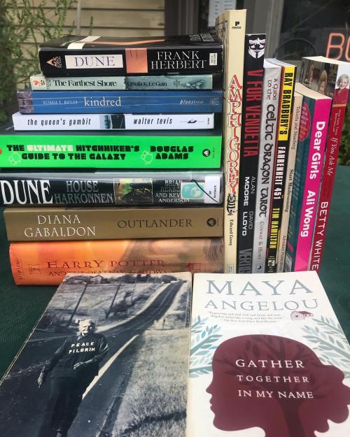 A stack of books including titles like "Dune," "Outlander," and works by Maya Angelou and Betty White.