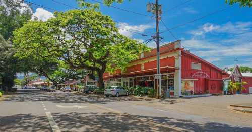 A vibrant street scene featuring colorful shops, lush trees, and clear blue skies in a small town.