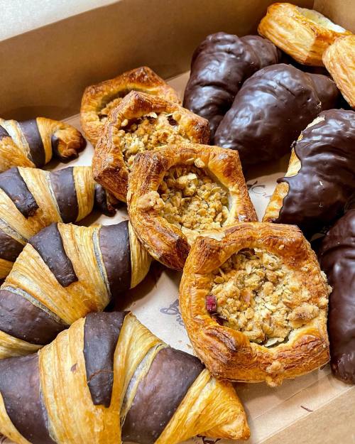 A box of assorted pastries, including chocolate croissants and nut-filled danishes, beautifully arranged.