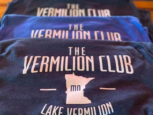Three t-shirts stacked, featuring "The Vermilion Club" and a Minnesota map outline, with "Lake Vermilion" text.