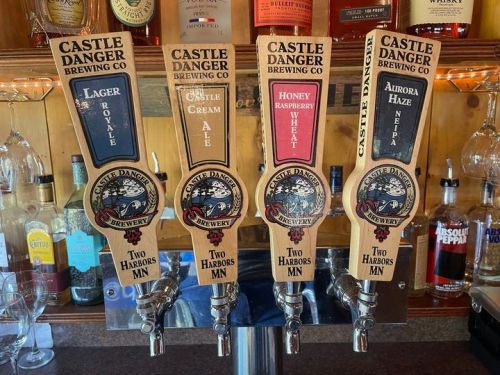 Four beer taps from Castle Danger Brewing Co., featuring Lager Royale, Honey Raspberry Wheat, and Aurora Haze.