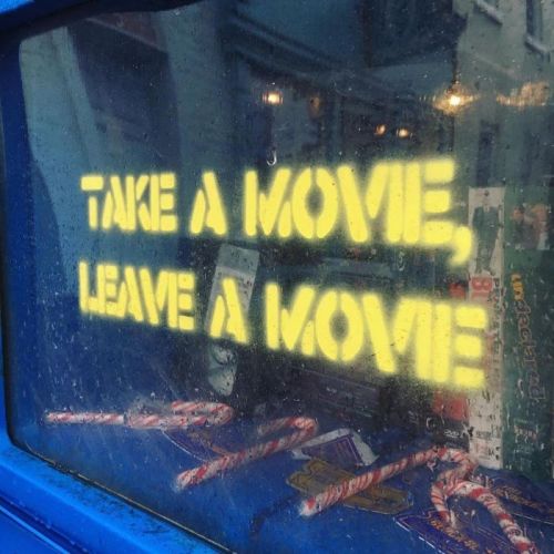 A window with a foggy surface displaying the text: "Take a movie, leave a movie," with candy canes below.