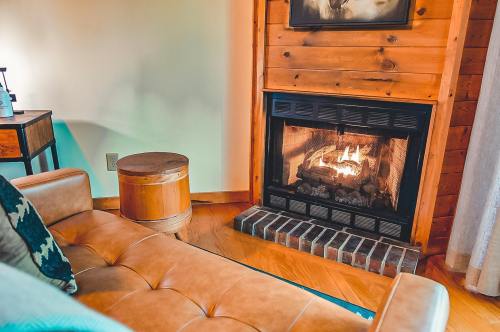 Cozy living room with a wooden fireplace, a leather couch, and a small round table beside it. Warm and inviting atmosphere.