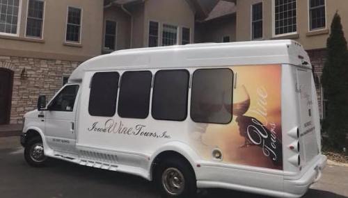 A white shuttle bus with a wine-themed design parked outside a building.