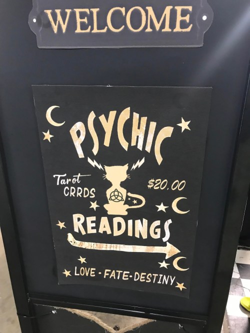 A sign advertising psychic readings, featuring tarot cards, priced at $20, with themes of love, fate, and destiny.