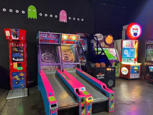 A colorful arcade featuring ice ball and basketball games, with a dark wall and playful ghost decorations.