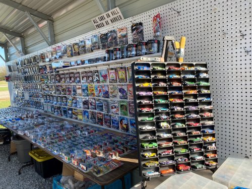 A display of collectible toy cars and action figures arranged on shelves at a market stall.