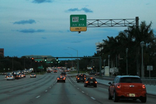 Traffic on a highway at dusk, with a sign indicating "A1A Only" and cars moving in both directions.