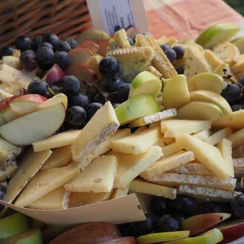 A platter of assorted cheeses, apple slices, and grapes arranged on a table.