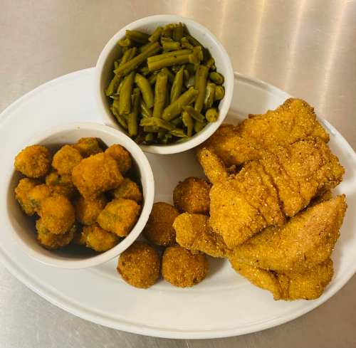 A platter featuring fried fish, green beans, and bowls of fried okra and cornbread balls.