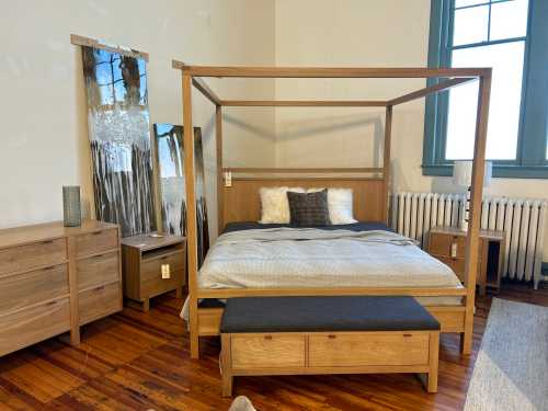 A cozy bedroom featuring a wooden canopy bed, nightstands, a dresser, and a large mirror against a light wall.