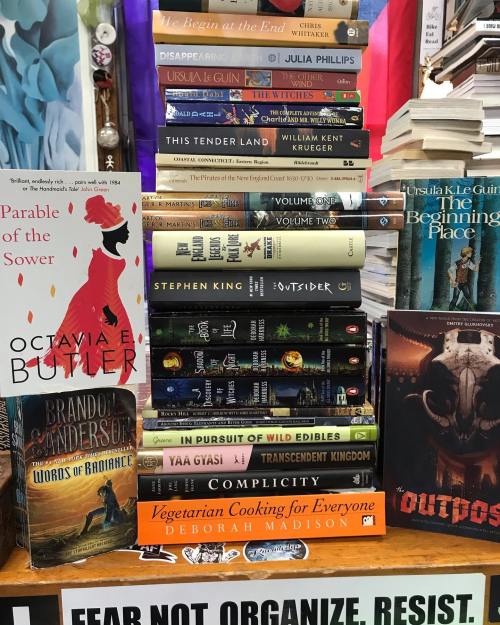 A stack of books featuring titles by Octavia Butler, Stephen King, and others, with a colorful background.