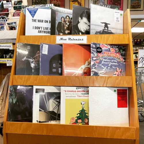 A wooden display rack featuring various vinyl records labeled "New Releases."