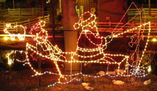 A festive display of Santa and a child in a boat, illuminated with colorful holiday lights.