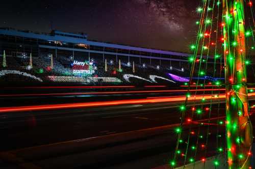 A festive scene with colorful Christmas lights and a decorated building under a starry night sky.