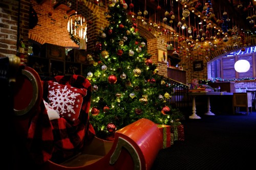 A cozy holiday scene featuring a decorated Christmas tree and a red sleigh with a snowflake pillow.