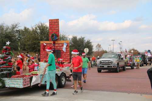 A festive parade with people in Santa hats, decorated floats, and a Christmas tree, celebrating the holiday season.