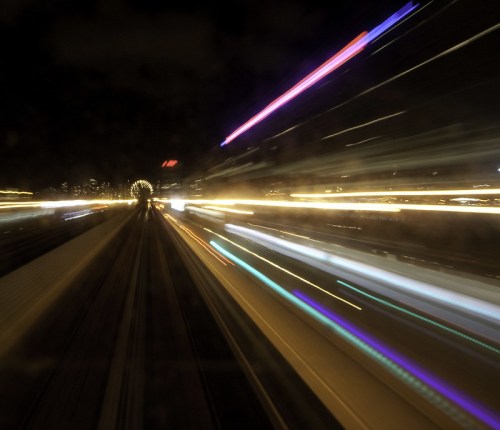 A blurred night scene of city lights and moving train tracks, creating a sense of speed and motion.
